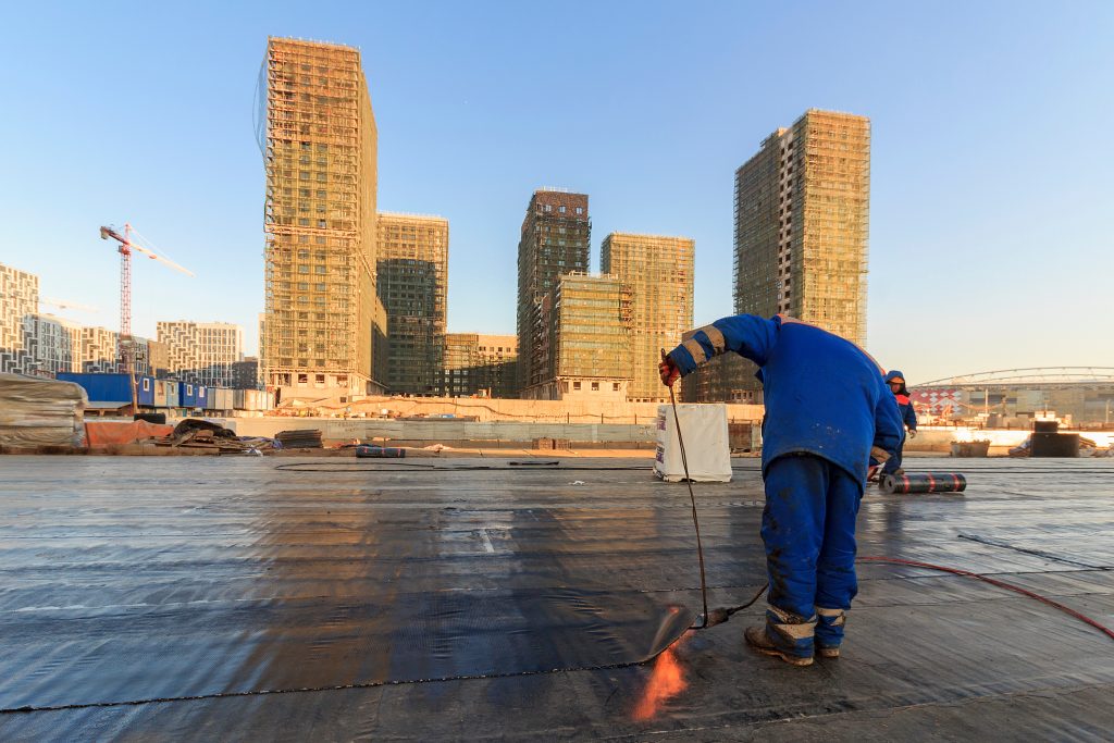 commercial roof coatings worker using torch on commercial roof