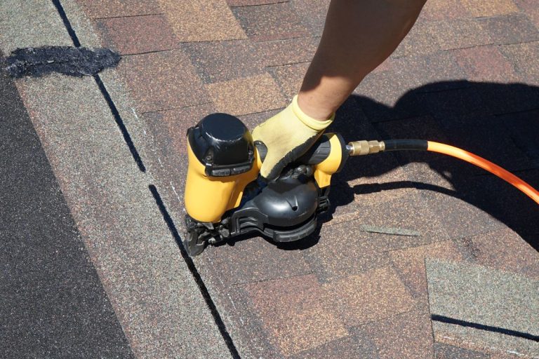 roof replacement worker using nail gun