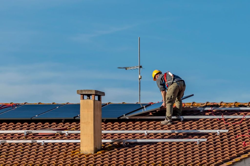 guy installing solar panels on top of tiles 